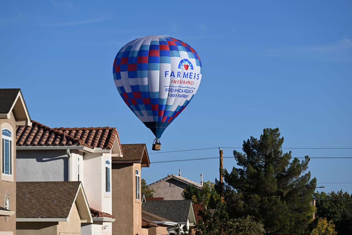 A colourful hot-air balloon floating low over houses in New Mexico in the early morning
