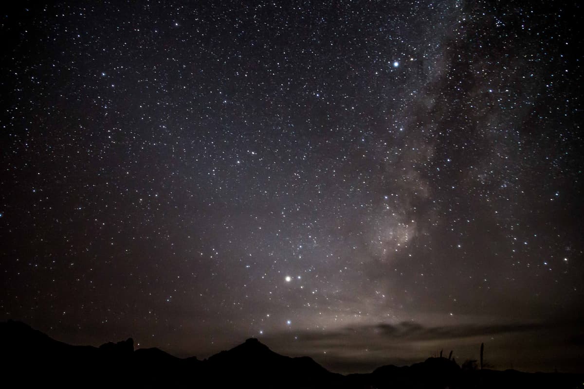 The Milky Way arching over the dark silhouette of the Chisos Mountains in Big Bend